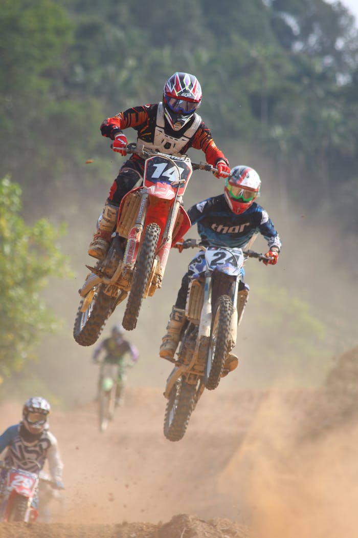 Exciting motocross race with bikers performing jumps on a dusty trail outdoors.